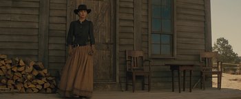 Movie still from “Jane Got a Gun” (2015), directed by Gavin O'Connor – A woman standing in front of an old wooden building; Wide shot, Low angle