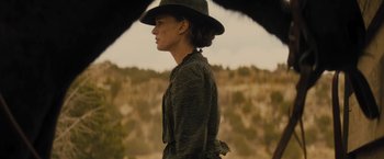 Movie still from “Jane Got a Gun” (2015), directed by Gavin O'Connor – A woman wearing a black hat and a black jacket; Medium shot, Low angle