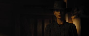 Movie still from “Jane Got a Gun” (2015), directed by Gavin O'Connor – A woman wearing a cowboy hat standing in a dark room; Close Up shot, Low angle