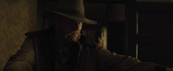 Movie still from “Jane Got a Gun” (2015), directed by Gavin O'Connor – A man in a cowboy hat is looking at the camera; Close Up shot, Over the shoulder angle