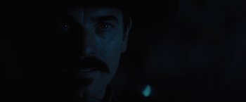 Movie still from “Jane Got a Gun” (2015), directed by Gavin O'Connor – A man's face in the dark; Close Up shot, Over the shoulder angle