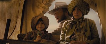 Movie still from “Jane Got a Gun” (2015), directed by Gavin O'Connor – A man and two children sitting in a wagon; Medium shot, Low angle