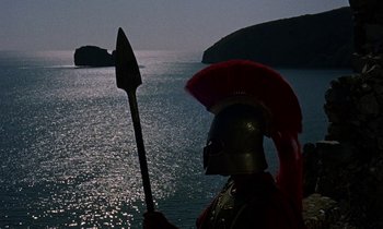 Movie still from “Jason and the Argonauts” (1963), directed by Don Chaffey – A man in a helmet holding a spear in front of the ocean; Extreme Wide shot, High angle