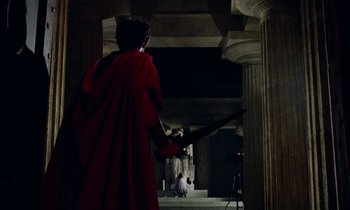 Movie still from “Jason and the Argonauts” (1963), directed by Don Chaffey – A man in a red robe holding a sword in front of a woman in a white dress; Wide shot, Low angle