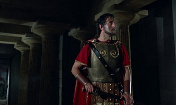 Movie still from “Jason and the Argonauts” (1963), directed by Don Chaffey – A man dressed as a roman centurion holding a sword in front of columns; Medium shot, Low angle