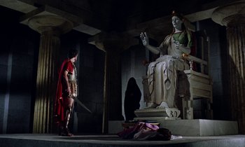 Movie still from “Jason and the Argonauts” (1963), directed by Don Chaffey – A woman dressed as a roman soldier standing in front of a statue; Wide shot, Low angle