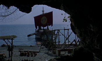 Movie still from “Jason and the Argonauts” (1963), directed by Don Chaffey – A boat with a clock on the side of it in the water; Extreme Wide shot, High angle