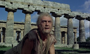 Movie still from “Jason and the Argonauts” (1963), directed by Don Chaffey – An old man with a long beard is sitting in front of a building; Medium shot, Low angle