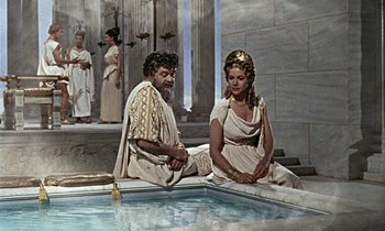 Movie still from “Jason and the Argonauts” (1963), directed by Don Chaffey – A man and a woman sitting in front of a fountain; Medium shot, High angle