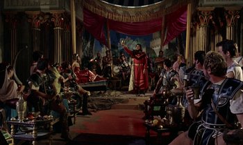 Movie still from “Jason and the Argonauts” (1963), directed by Don Chaffey – A group of people sitting in a room with a man in a red robe; Wide shot, High angle
