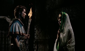 Movie still from “Jason and the Argonauts” (1963), directed by Don Chaffey – A man and a woman holding torches in front of a stone wall; Medium shot, Over the shoulder angle