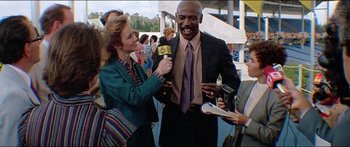 Movie still from “Jaws 3-D” (1983), directed by Joe Alves – A man in a suit is being interviewed by a reporter; Medium shot, Low angle