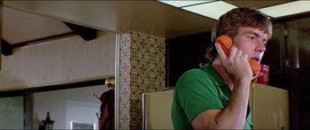 Movie still from “Jaws 3-D” (1983), directed by Joe Alves – A man in a green shirt is talking on the phone; Close Up shot, Low angle