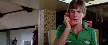 Movie still from “Jaws 3-D” (1983), directed by Joe Alves – A man holding an orange phone up to his ear; Close Up shot, Low angle