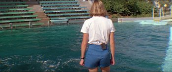 Movie still from “Jaws 3-D” (1983), directed by Joe Alves – A woman standing in a body of water with a cell phone; Wide shot, High angle