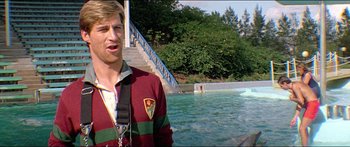 Movie still from “Jaws 3-D” (1983), directed by Joe Alves – A man standing in front of a swimming pool; Medium shot, Over the shoulder angle