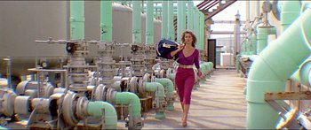 Movie still from “Jaws 3-D” (1983), directed by Joe Alves – A woman in a purple dress walking through pipes holding a bag; Wide shot, Low angle