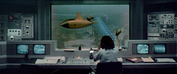 Movie still from “Jaws 3-D” (1983), directed by Joe Alves – A woman in a control room looking at an airplane in the air; Wide shot, High angle