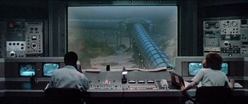 Movie still from “Jaws 3-D” (1983), directed by Joe Alves – A man is looking out of a window at an aquarium; Wide shot, Low angle