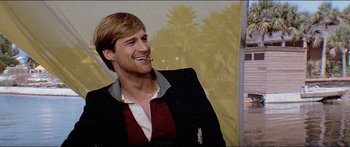 Movie still from “Jaws 3-D” (1983), directed by Joe Alves – A man in a suit smiling for the camera; Close Up shot, Over the shoulder angle