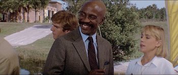 Movie still from “Jaws 3-D” (1983), directed by Joe Alves – A man in a suit and tie smiling for the camera; Close Up shot, Low angle