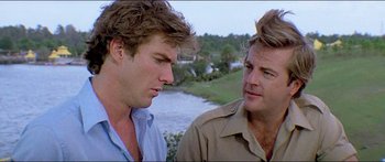 Movie still from “Jaws 3-D” (1983), directed by Joe Alves – Two men are standing next to each other near a body of water; Close Up shot, Over the shoulder angle