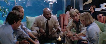 Movie still from “Jaws 3-D” (1983), directed by Joe Alves – A group of people sitting around a table; Medium shot, Low angle