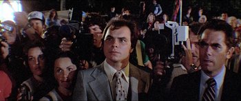 Movie still from “Jaws 3-D” (1983), directed by Joe Alves – A man in a suit and tie in a crowd of onlookers; Close Up shot, Low angle
