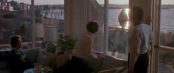 Movie still from “Jaws: The Revenge” (1987), directed by Joseph Sargent – A woman sitting in front of a window looking out at the water; Wide shot, Over the shoulder angle