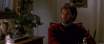 Movie still from “Jaws: The Revenge” (1987), directed by Joseph Sargent – A man sitting in front of a plant in a room; Close Up shot, Over the shoulder angle