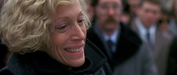 Movie still from “Jaws: The Revenge” (1987), directed by Joseph Sargent – A person smiling with another person in the background; Close Up shot, Over the shoulder angle