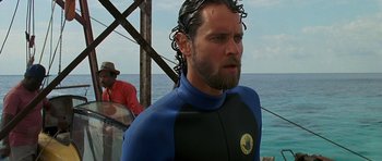 Movie still from “Jaws: The Revenge” (1987), directed by Joseph Sargent – A man in a wetsuit standing next to the ocean; Close Up shot, Over the shoulder angle