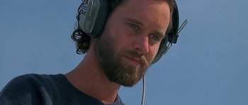 Movie still from “Jaws: The Revenge” (1987), directed by Joseph Sargent – A man with a beard wearing headphones and a t - shirt; Close Up shot, Low angle