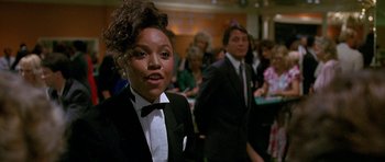 Movie still from “Jaws: The Revenge” (1987), directed by Joseph Sargent – A woman in a black suit and a man in a black suit; Medium shot, Over the shoulder angle