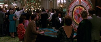 Movie still from “Jaws: The Revenge” (1987), directed by Joseph Sargent – A group of people standing around a game table; Wide shot, High angle