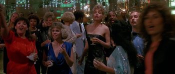 Movie still from “Jaws: The Revenge” (1987), directed by Joseph Sargent – A group of people standing in a room with drinks; Medium shot, Over the shoulder angle