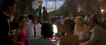 Movie still from “Jaws: The Revenge” (1987), directed by Joseph Sargent – A group of people sitting at a table in front of a window; Medium shot, Over the shoulder angle