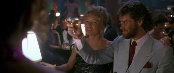 Movie still from “Jaws: The Revenge” (1987), directed by Joseph Sargent – A woman holding up a glass of wine in front of a crowd; Medium shot, Low angle