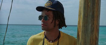 Movie still from “Jaws: The Revenge” (1987), directed by Joseph Sargent – A man with dreadlocks wearing sunglasses and a hat; Close Up shot, Low angle