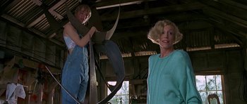 Movie still from “Jaws: The Revenge” (1987), directed by Joseph Sargent – Two women in overalls are standing in a barn; Medium shot, Low angle