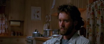 Movie still from “Jaws: The Revenge” (1987), directed by Joseph Sargent – A man with a beard is sitting in a kitchen; Close Up shot, Low angle
