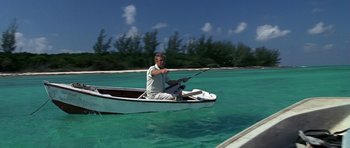 Movie still from “Jaws: The Revenge” (1987), directed by Joseph Sargent – A man is in a boat in the water holding a fishing rod; Wide shot, High angle