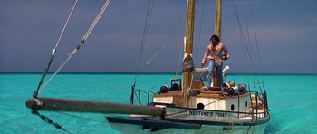 Movie still from “Jaws: The Revenge” (1987), directed by Joseph Sargent – A man standing on the side of a boat in the ocean; Extreme Wide shot, High angle