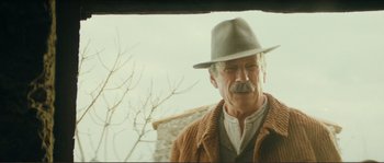 Movie still from “Jean de Florette” (1986), directed by Claude Berri – An older man wearing a hat standing in front of a tree; Close Up shot, Low angle