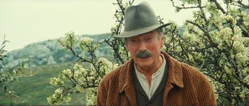 Movie still from “Jean de Florette” (1986), directed by Claude Berri – An older man wearing a hat standing next to a tree; Close Up shot, Low angle