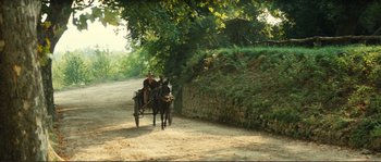 Movie still from “Jean de Florette” (1986), directed by Claude Berri – Two people riding a horse and buggy down a dirt road; Extreme Wide shot, High angle