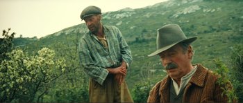 Movie still from “Jean de Florette” (1986), directed by Claude Berri – A man in a hat standing next to another man in a hat; Medium shot, Low angle