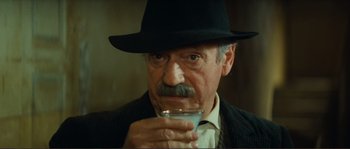 Movie still from “Jean de Florette” (1986), directed by Claude Berri – An older man wearing a black hat drinking a glass of water; Close Up shot, Low angle