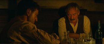 Movie still from “Jean de Florette” (1986), directed by Claude Berri – Two men sitting at a table with a glass; Close Up shot, Over the shoulder angle