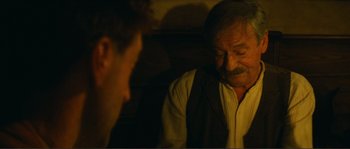 Movie still from “Jean de Florette” (1986), directed by Claude Berri – A man sitting next to another man in a dark room; Close Up shot, Over the shoulder angle